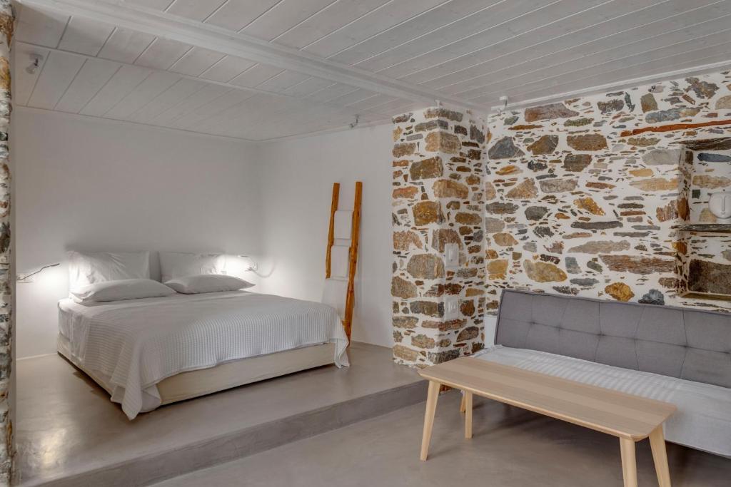 een slaapkamer met een bed en een stenen muur bij Artdecosyros Junior in Ano Syros