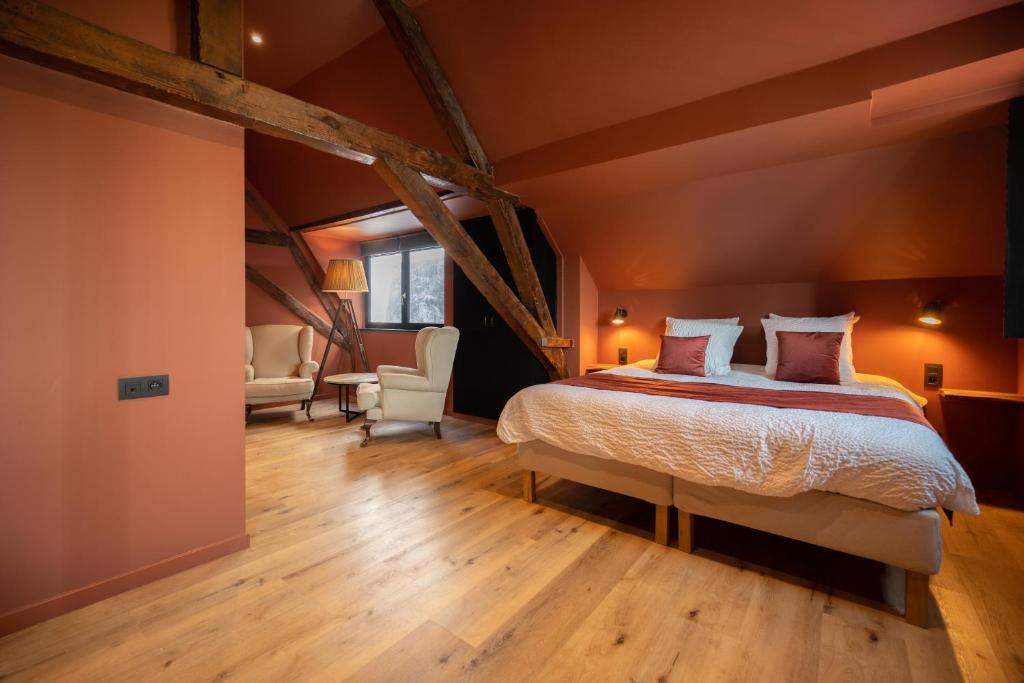 a bedroom with a bed and chairs in a room at Guest House La Civière d'or in Bruges