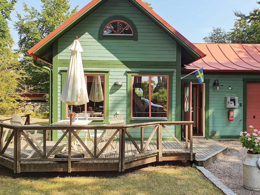 ein grünes Haus mit einer Terrasse und einem Sonnenschirm in der Unterkunft Holiday home in Ronneby in Ronneby