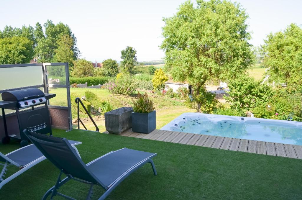 einen Hinterhof mit einem Grill und Stühlen sowie einem Pool in der Unterkunft Le Toit Penché in Tardinghen
