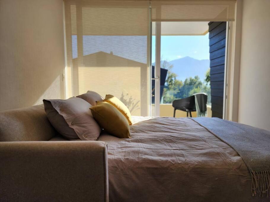 a bedroom with a bed with pillows and a large window at Condominio Alta Vista Pucón in Pucón