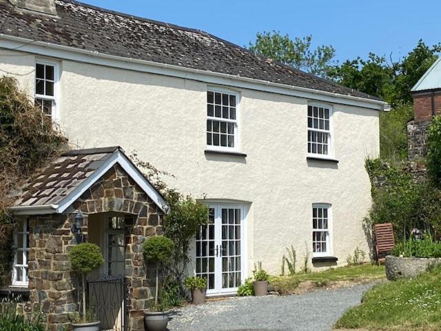 uma casa de tijolos brancos com janelas e uma entrada em The Cottage em Exeter