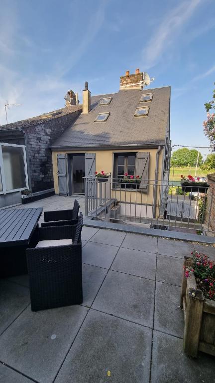een huis met een patio met twee banken bij Maison du quai à Saint Valéry sur Somme in Saint-Valery-sur-Somme