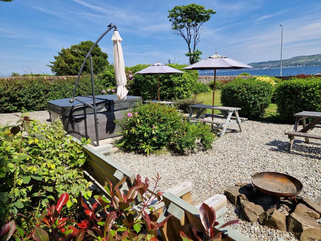 a garden with an umbrella and a table and benches at Firthview House in Kirn