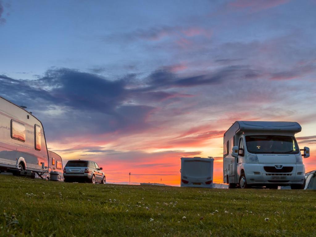 due camper parcheggiati in un campo con il tramonto di GPtents Camping - Spa a Stavelot