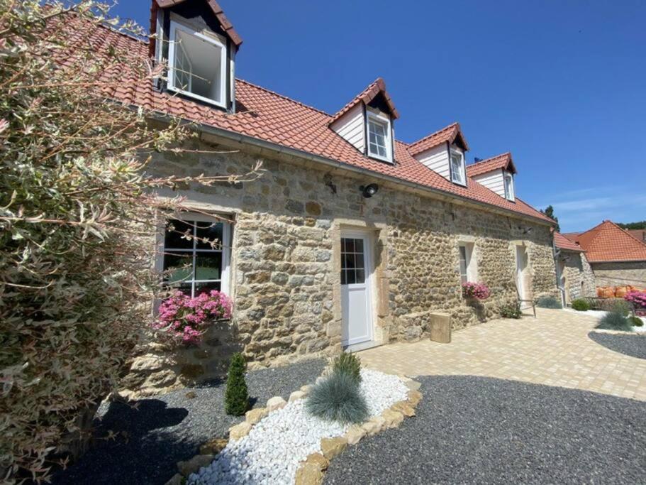 une maison en pierre avec une porte blanche et des fenêtres dans l'établissement la grange, à Offrethun