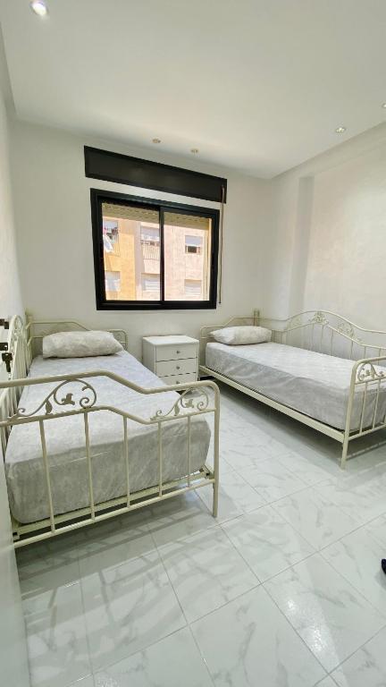een slaapkamer met twee bedden en een raam bij Big appartment near soccer stadium in Tangier in Tanger