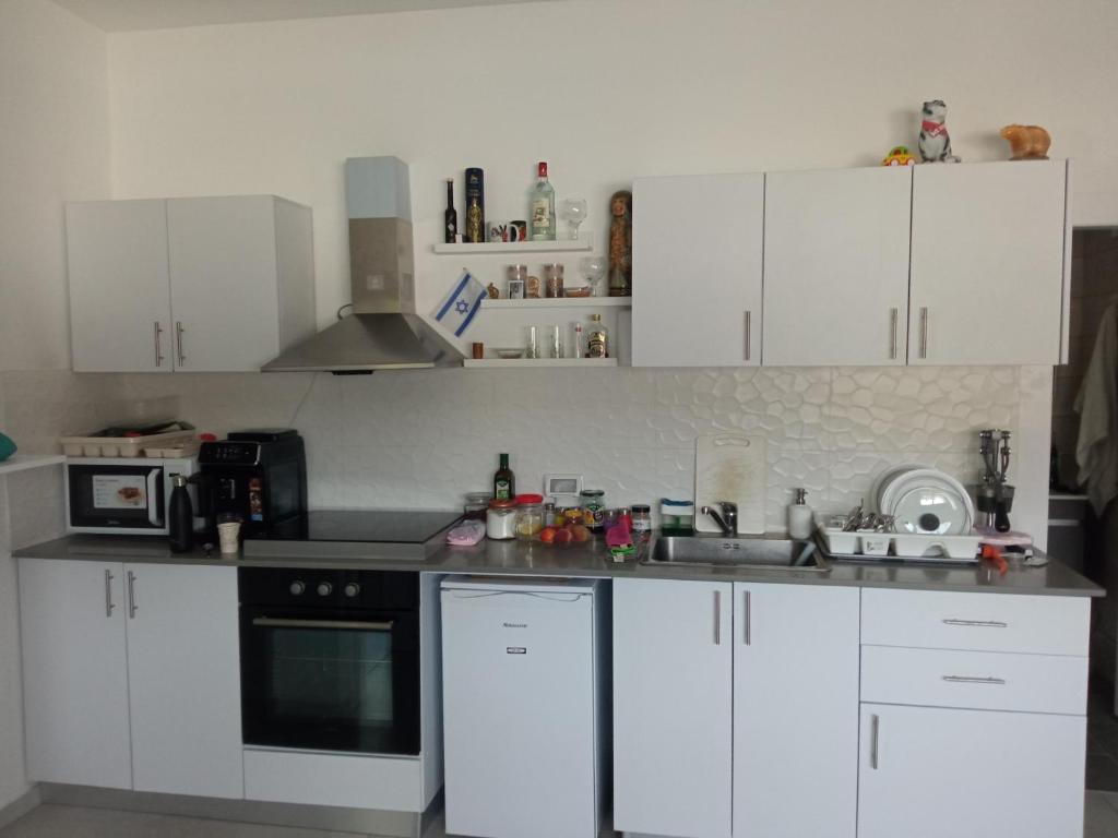 a white kitchen with white cabinets and a sink at Квартира с высокими потолками. in Migdal