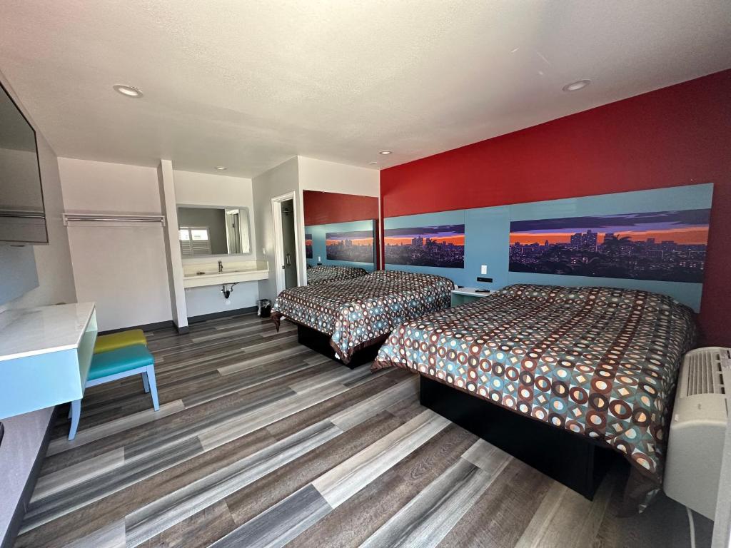 two beds in a hotel room with red walls at La Casa Motel, Los Angeles - Burbank Airport in Sun Valley