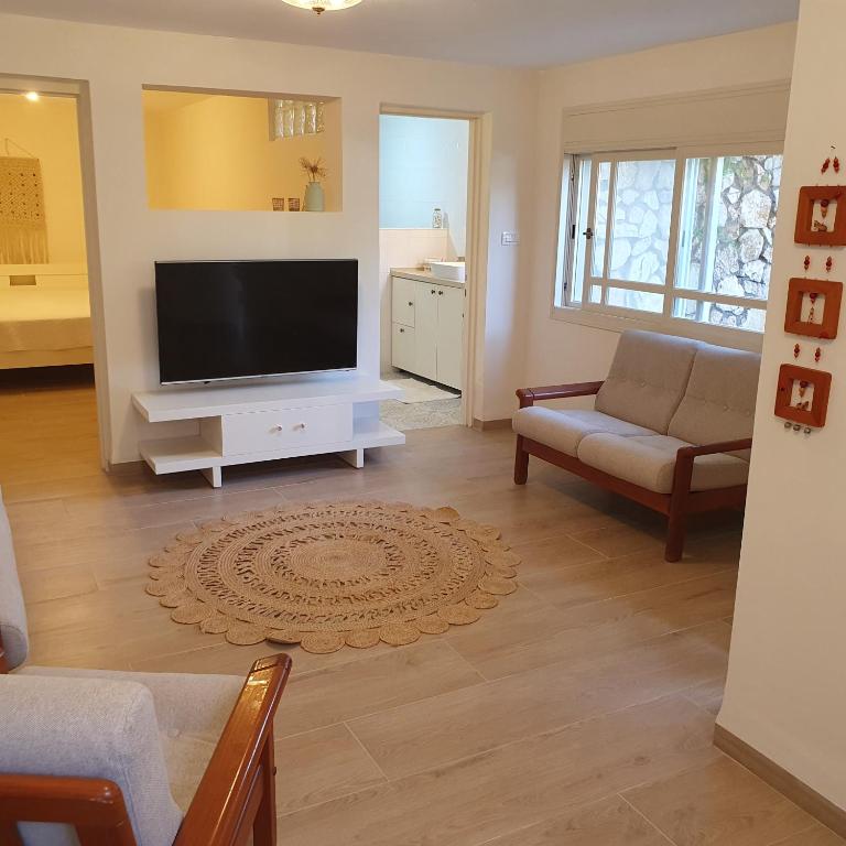 a living room with a flat screen tv and a couch at היחידה בגומא in Kefar Weradim