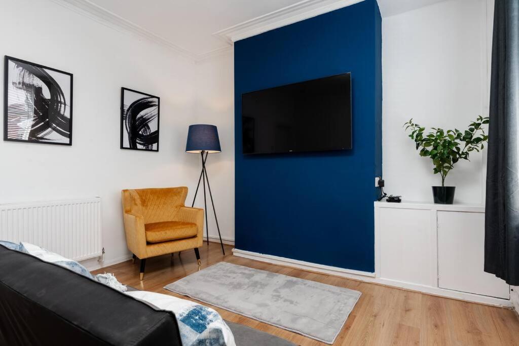 a living room with a blue wall and a couch and a chair at Manchester Urban Chic Hideaway in Manchester