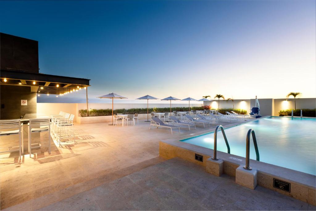 - une piscine avec des chaises, des tables et des parasols dans l'établissement Residence Inn by Marriott Merida, à Mérida