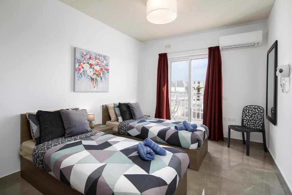 - une chambre avec 2 lits, un canapé et une fenêtre dans l'établissement Hilltop Apartments - Stylish Comfort Living close to the sea, Bugibba, à San Pawl il-Baħar