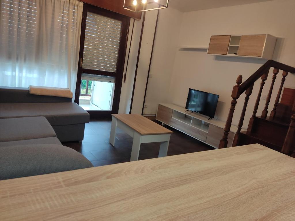 1 dormitorio con cama, sofá y TV en Duplex en Ris, en Noja