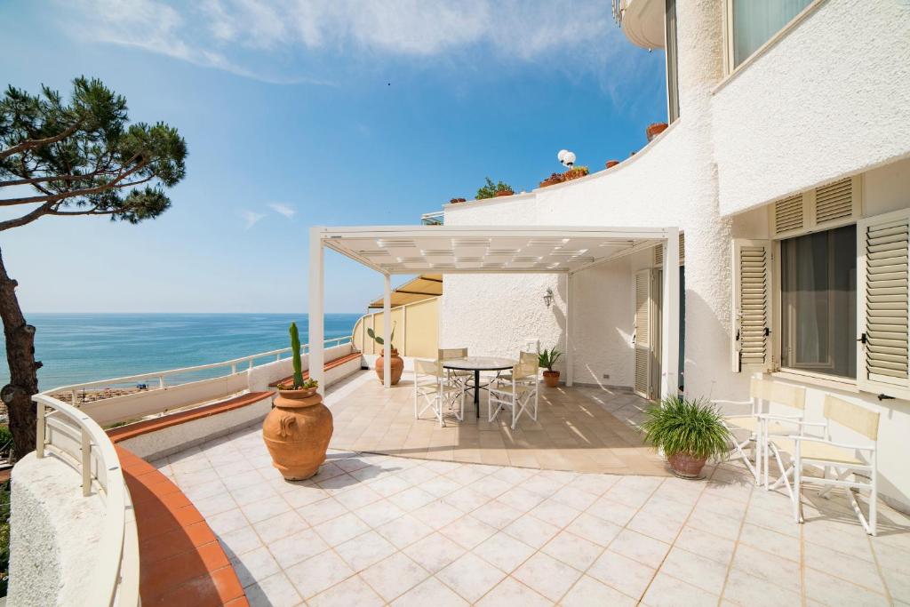 une terrasse avec une table et des chaises et l'océan dans l'établissement Vento Verde Apartments, à Sperlonga