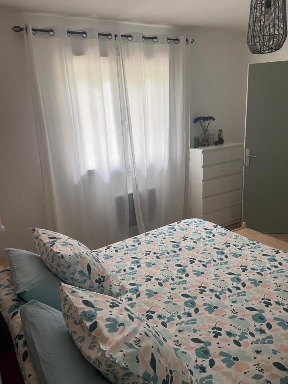 ein Schlafzimmer mit einem Bett mit einer Bettdecke und Kissen in der Unterkunft coconing et chaleureux T2 in Rochefort-du-Gard