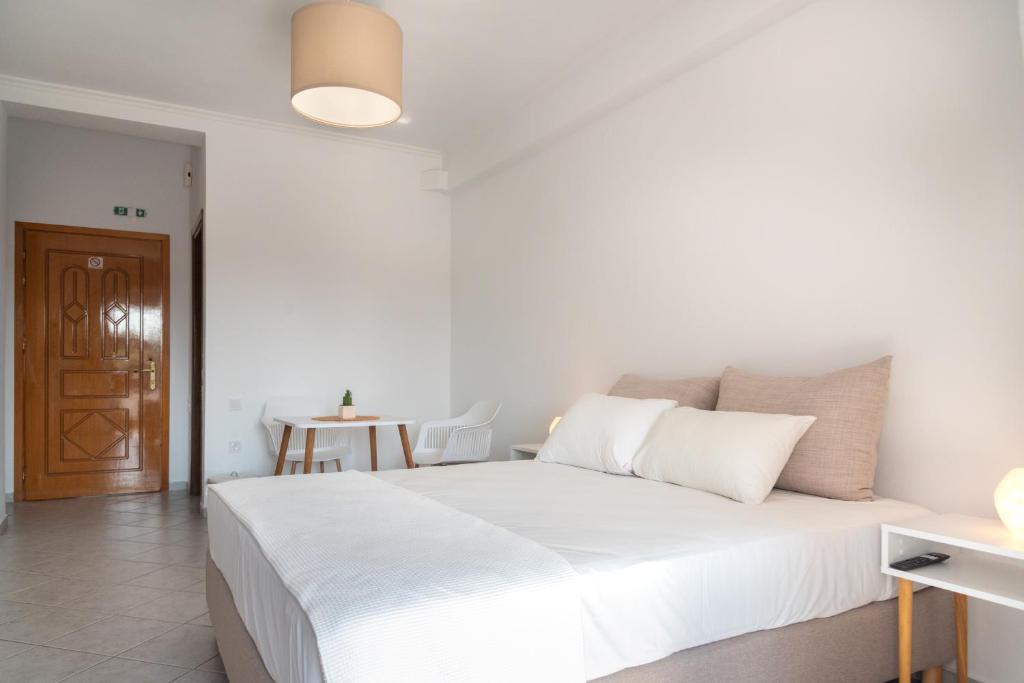 a white bed in a white room with a table at Villa Rodanthi Sivota in Syvota