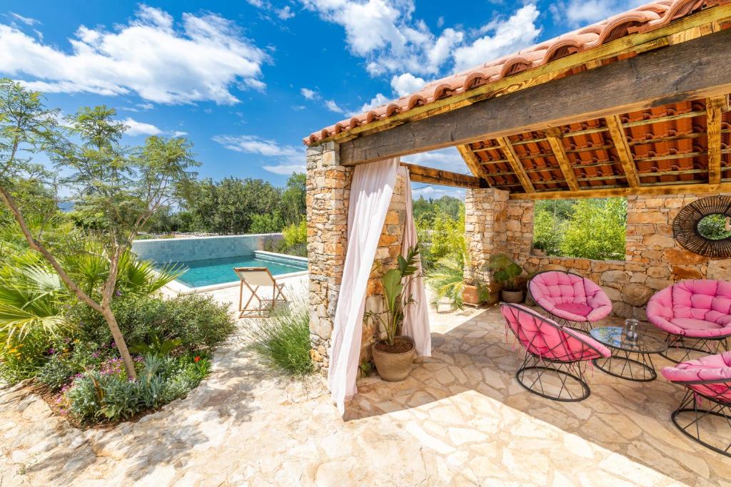 a patio with pink chairs and a pool at Mai's Cottage in Stari Grad