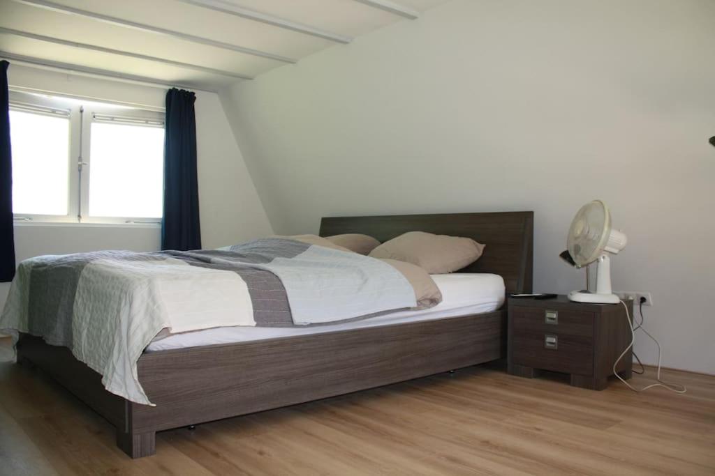 een slaapkamer met een bed en een bureau met een ventilator bij De Bosrand Unieke plek grenzend aan het bos in Castricum