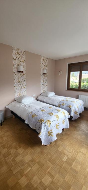 two beds in a large room with two windows at La Plante, tendance et design in Ornans