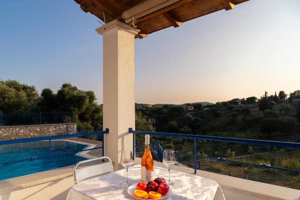a table with a bowl of fruit and a bottle of wine at Villa Rodanthi Sivota in Syvota