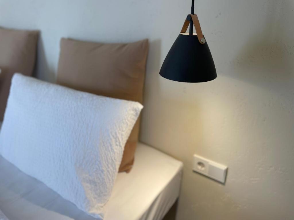 a black lamp hanging over a bed with a white pillow at Viva Properties in Ouranoupoli