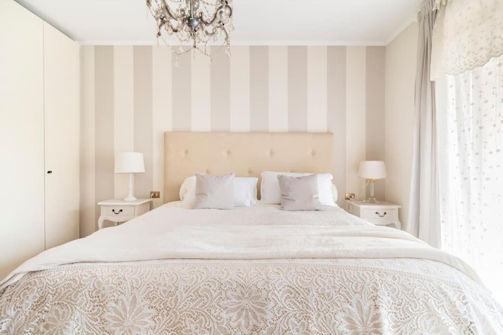 a bedroom with a large white bed with striped walls at Fiorenza House in Luisago