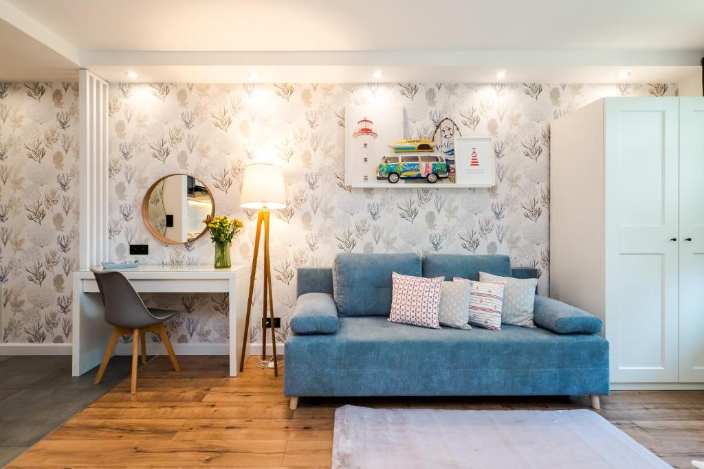 salon z niebieską kanapą i biurkiem w obiekcie Apartamenty Usteckie w Ustce