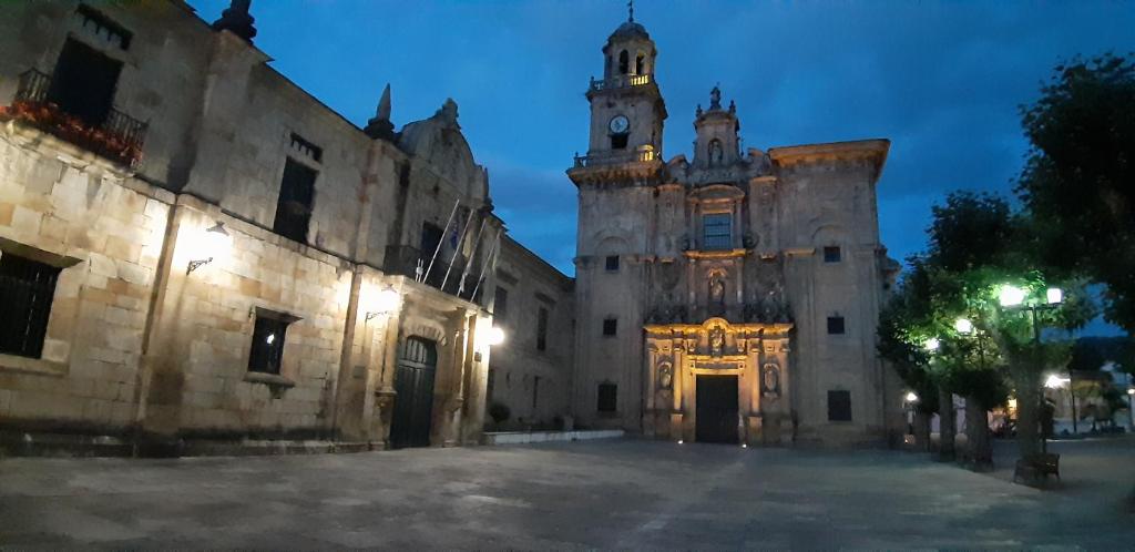 an old building with a clock tower at night at Entre Las Catedrales Campo y Mar 1 y 2 in Lourenzá