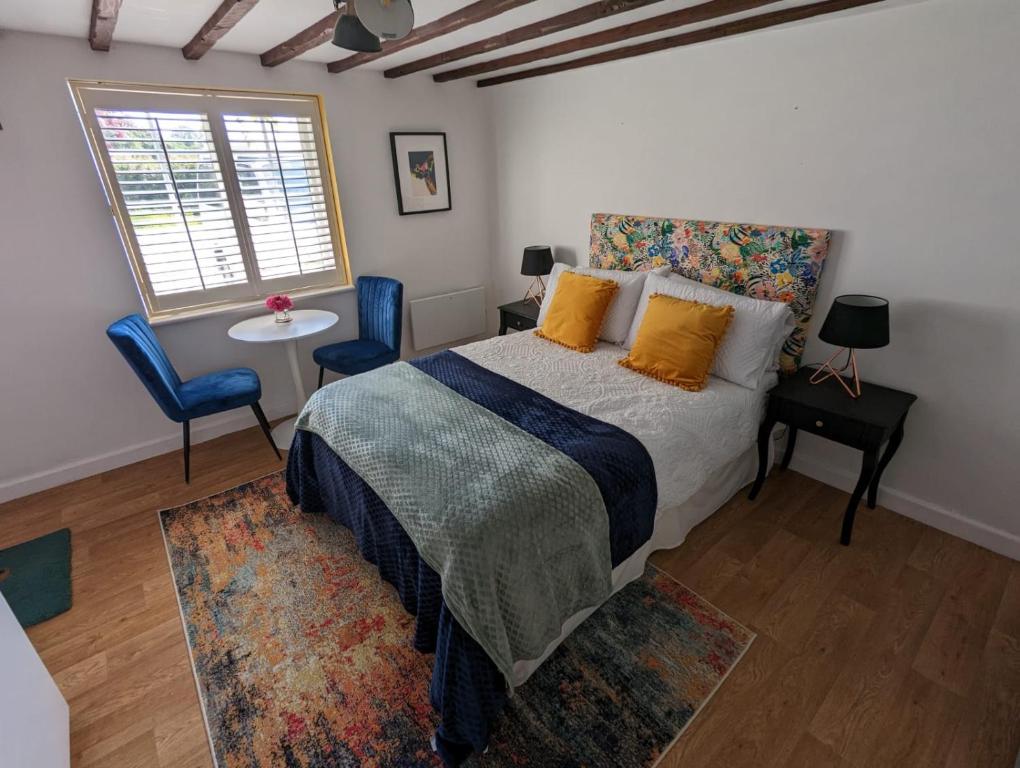 a bedroom with a bed and two chairs and a window at Sunrise Studio in Colchester