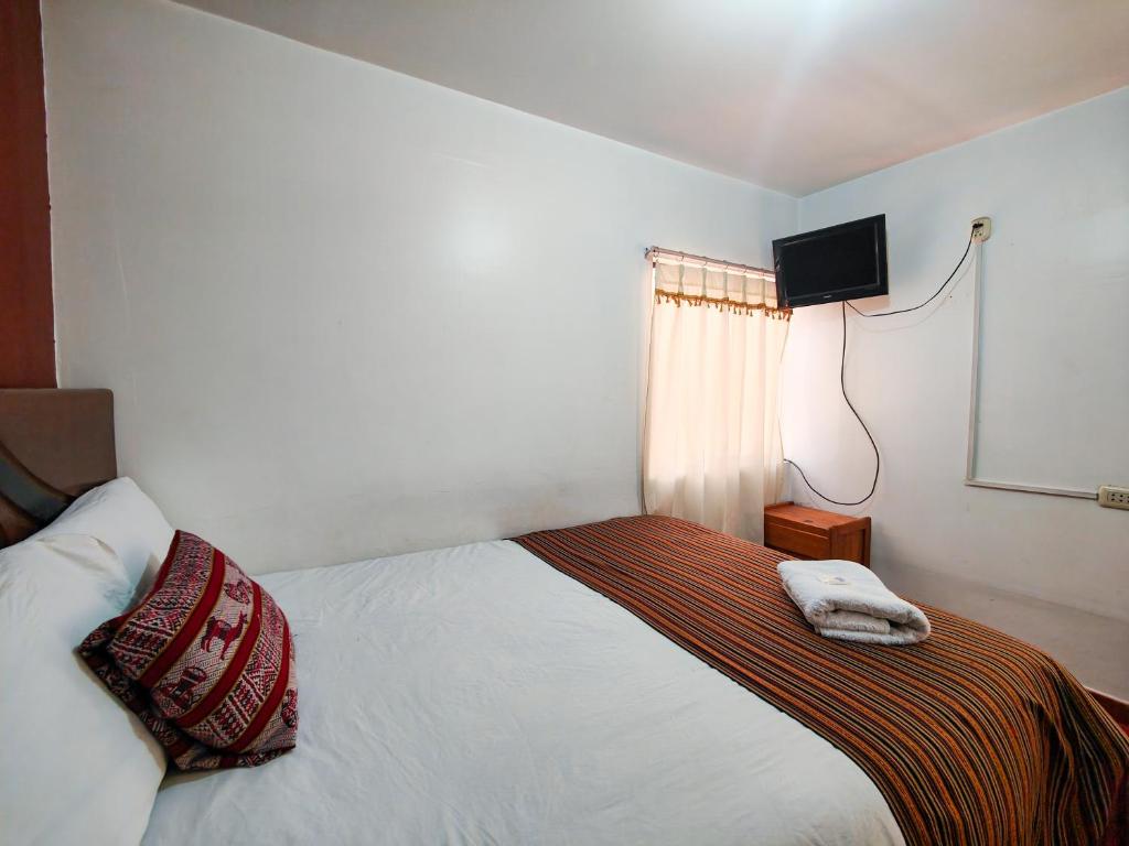 um quarto com uma cama e uma televisão na parede em HOSTAL QORI KANCHA'S INN em Cusco
