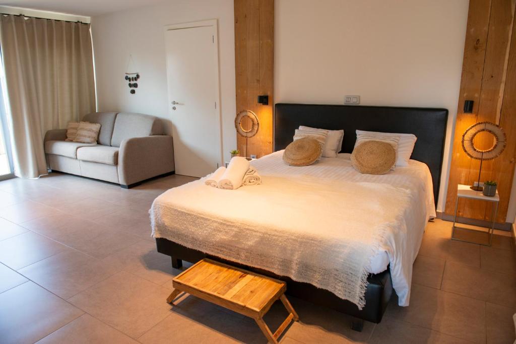 a bedroom with a large bed and a couch at Boutique Hotel Het Zoete Zijn in Borgloon