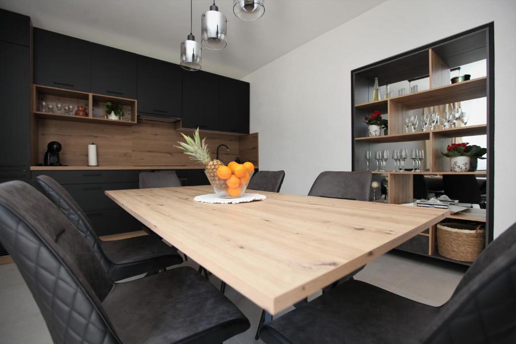 uma sala de jantar com uma mesa de madeira e armários pretos em Blue Sky Trogir em Plano