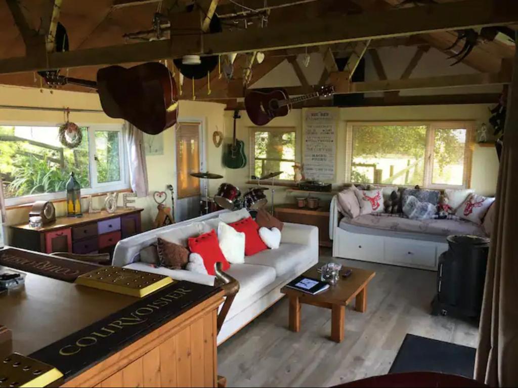 ein Wohnzimmer mit einem Sofa und einem Tisch in der Unterkunft Angies Den - quirky cabin with hot tub & views in Llanasa