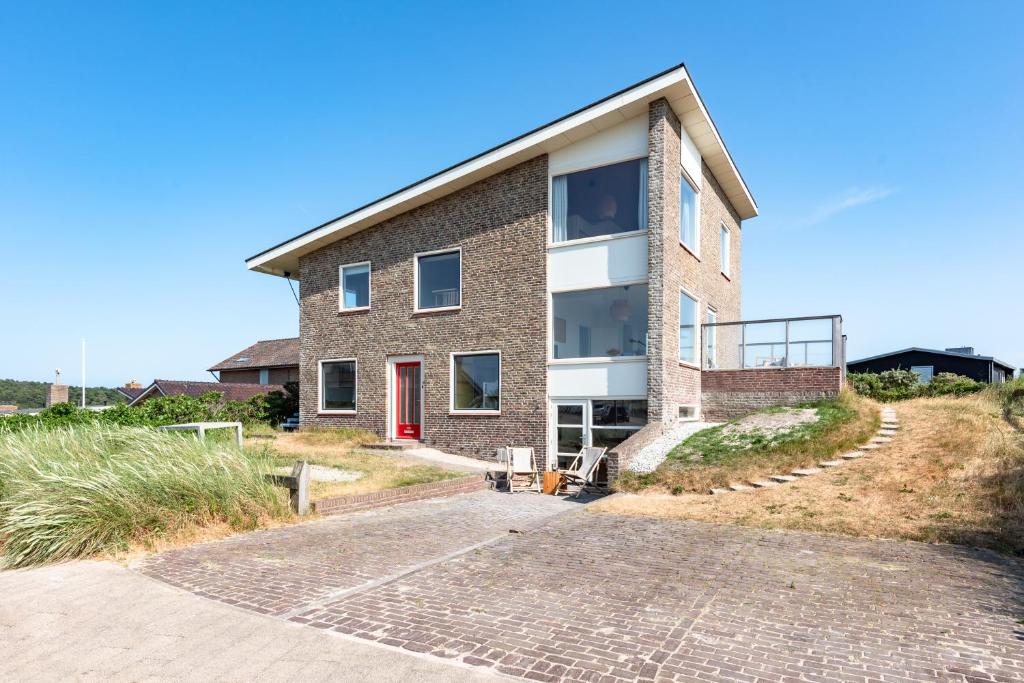 een stenen huis met een rode deur op een heuvel bij Zeezicht Villa Zee aan het strand in Bergen aan Zee