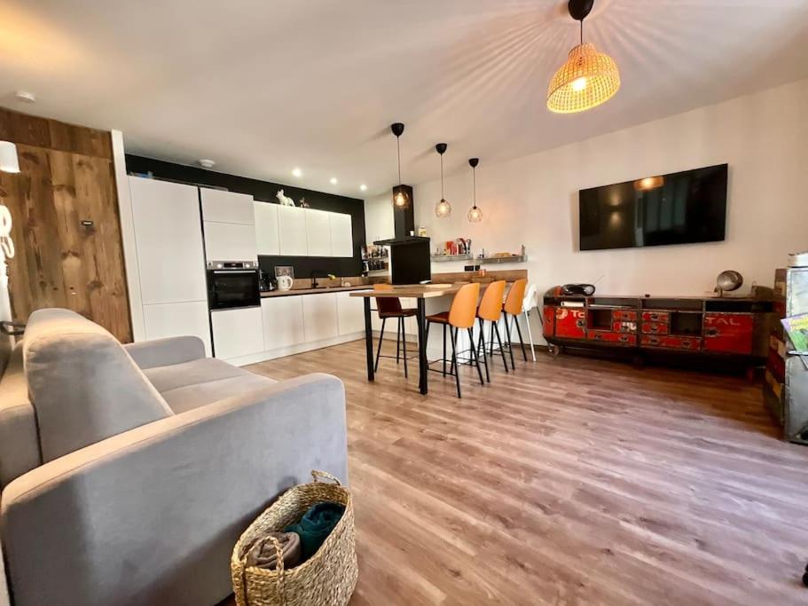 un salon avec un canapé et une table avec des chaises dans l'établissement L’Appart Gabriela, gîte de standing hypercentre, à Gérardmer