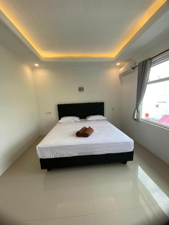 a bedroom with a bed with a pair of shoes on it at New Anugrah Hotel in Teluk Nara