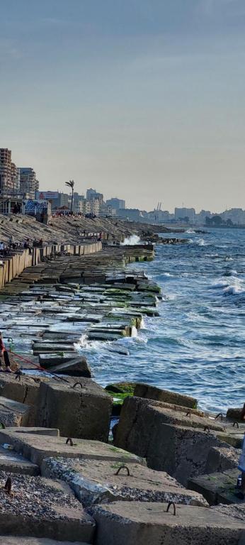a beach with rocks and the ocean with waves at شقة مفروشة 5 سراير في كامب شيزار 