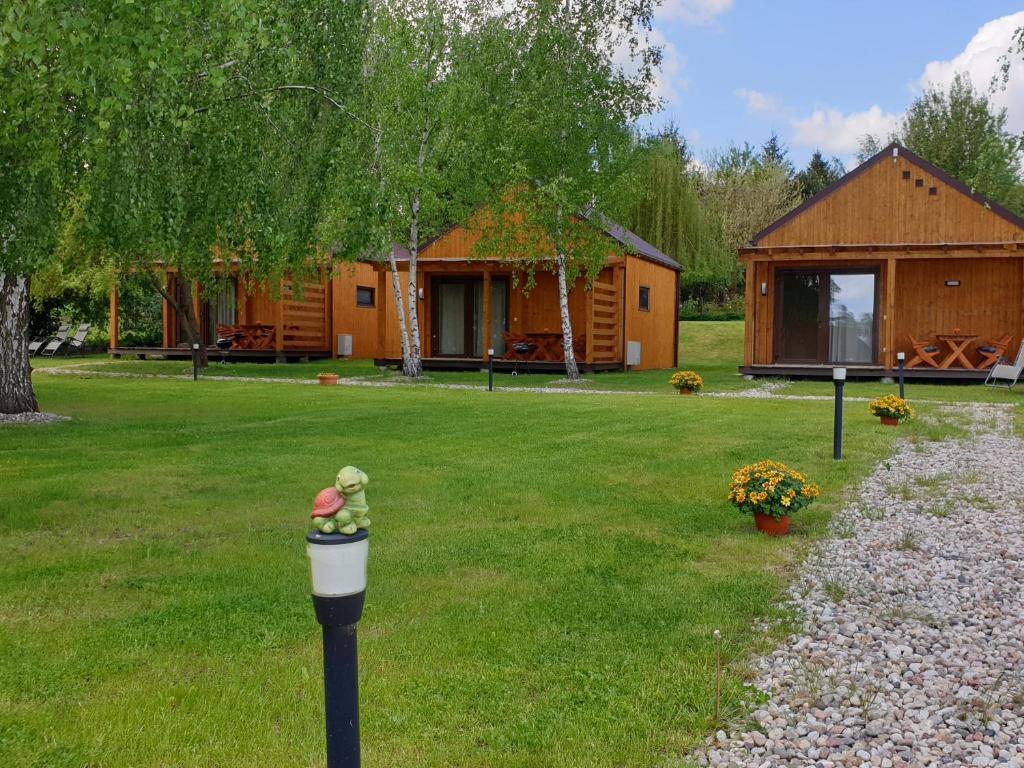 a log cabin with a yard with a house at Kamienny Ogród Holiday Park in Mikołajki