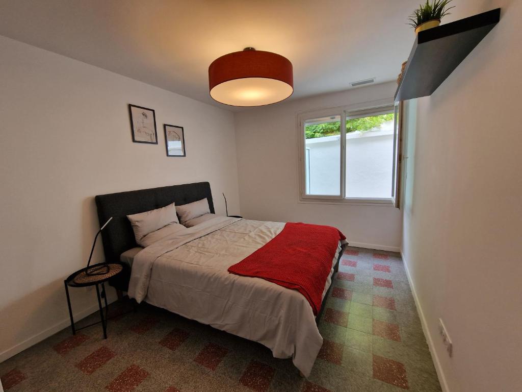 a bedroom with a bed with a red blanket and a window at maison PING ,en face des arènes in Béziers