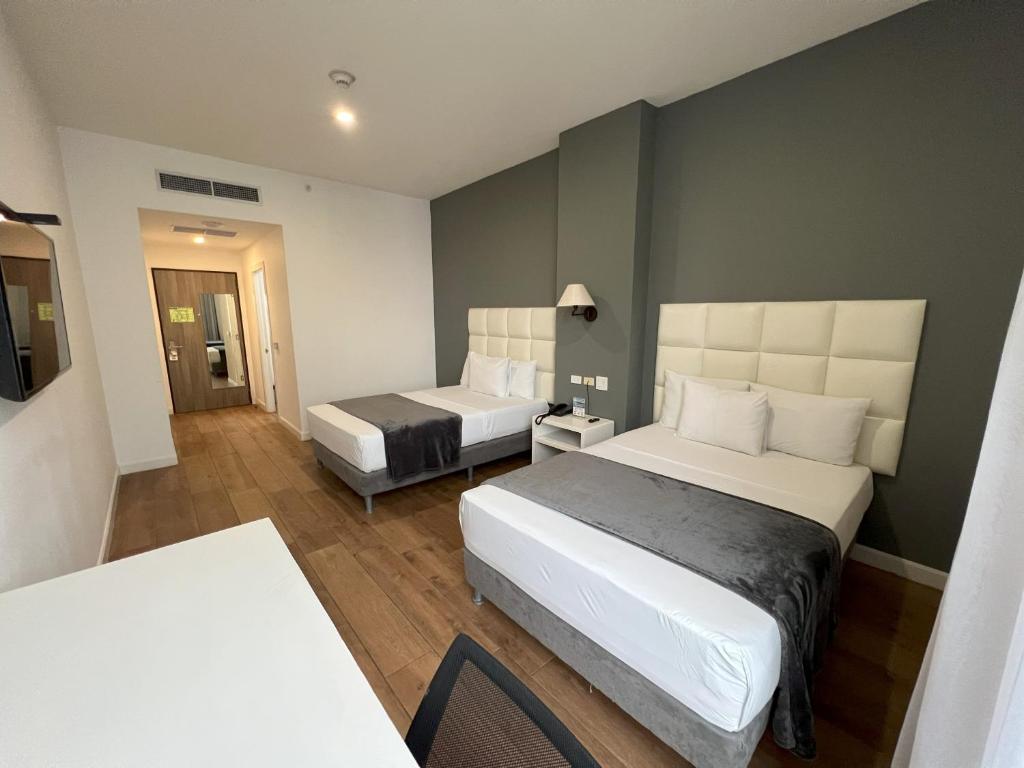 ein Hotelzimmer mit 2 Betten und einem Tisch in der Unterkunft Hotel Mio Panamá in Panama-Stadt
