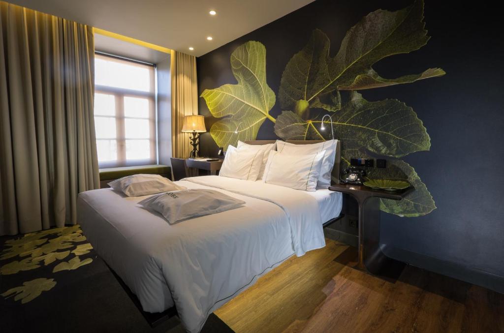 リスボンにあるFigueira by The Beautique Hotels & Spaの大きな植物が壁に置かれたベッド付きのホテルルームです。