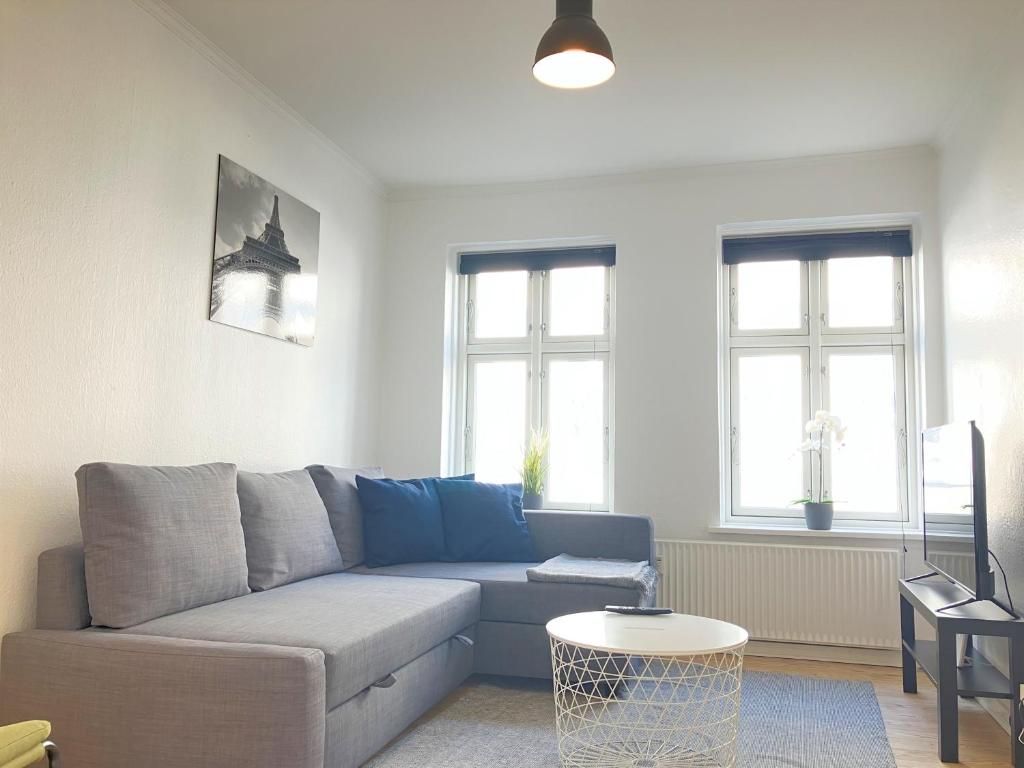 a living room with a blue couch and two windows at 1 Bedroom Apartment In Kolding City Center in Kolding