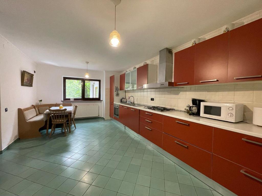 a kitchen with red cabinets and a table with a microwave at Pensiunea La Maison in Bran