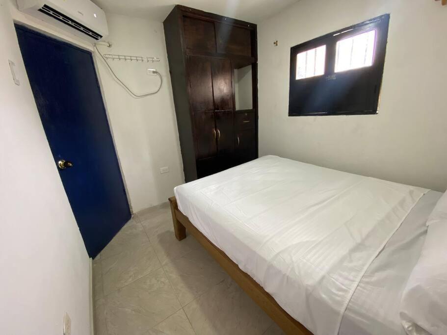 um pequeno quarto com uma cama branca e uma janela em Apartamento en Getsemaní em Cartagena das Índias