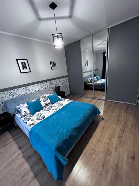 ein Schlafzimmer mit einem blauen Bett und einem Spiegel in der Unterkunft Apartament Walczaka 47 MIEJSCE PARKINGOWE in Gorzów Wielkopolski