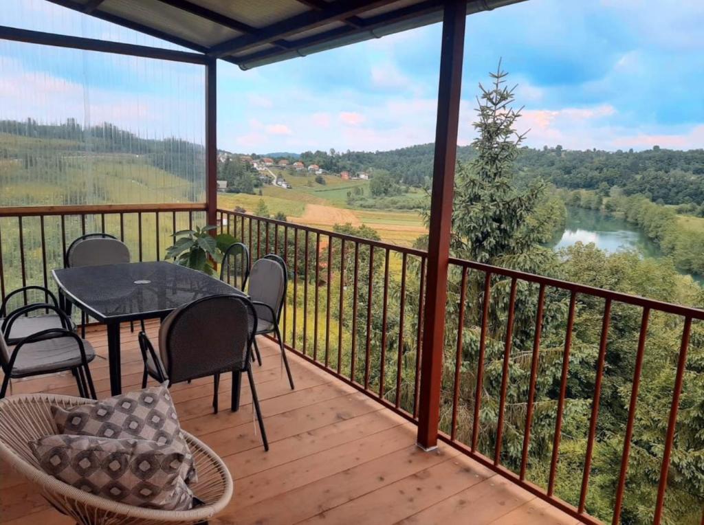 a balcony with a table and chairs and a view of a river at Kuća Schunko in Duga Resa
