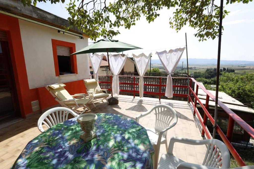 een tafel met stoelen en een parasol op een balkon bij [cav Maura] relax toscana in Crocina
