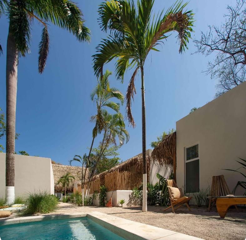 a villa with a swimming pool and palm trees at Yaxa Hotel Nosara in Nosara