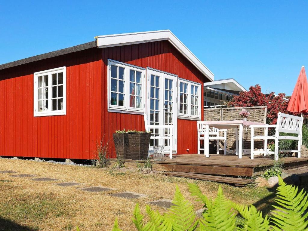 Karrebæksmindeにある3 person holiday home in Karrebæksminde-By Traumのデッキと2つの白い椅子がある赤い家